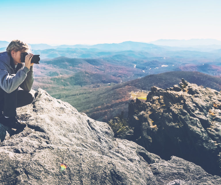 Man with a camera on top of a cliff