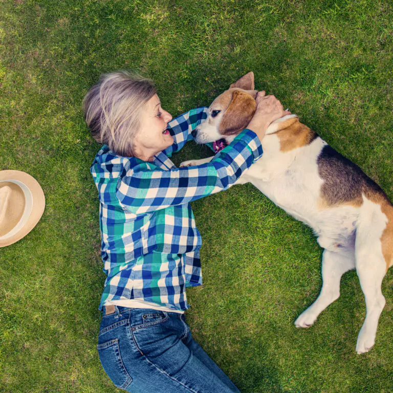 Beautiful senior woman with her dog lying on grass